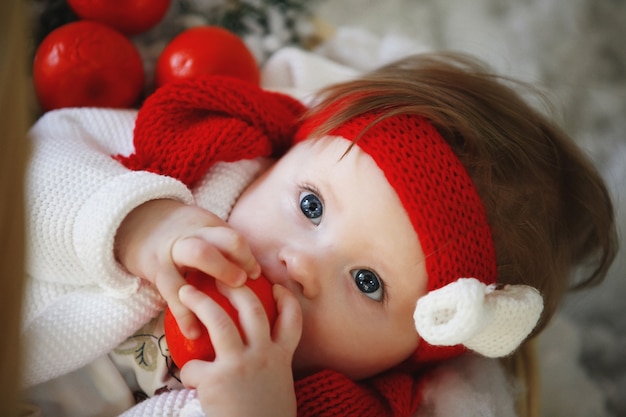 A baby in a red cap with balls in the New Year's interior.