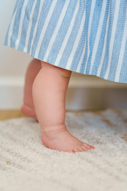 A baby's feet are visible in a blue striped dress.