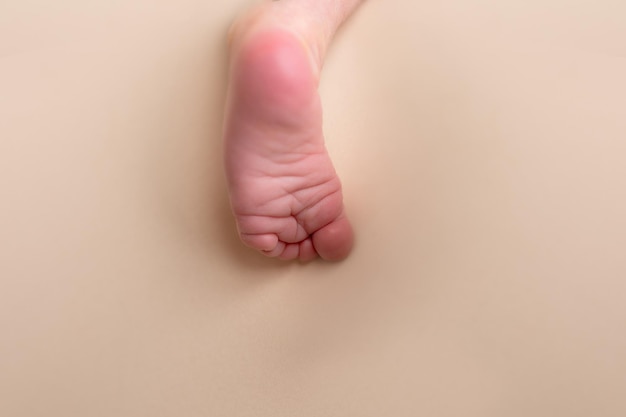 A baby's foot is on a beige background