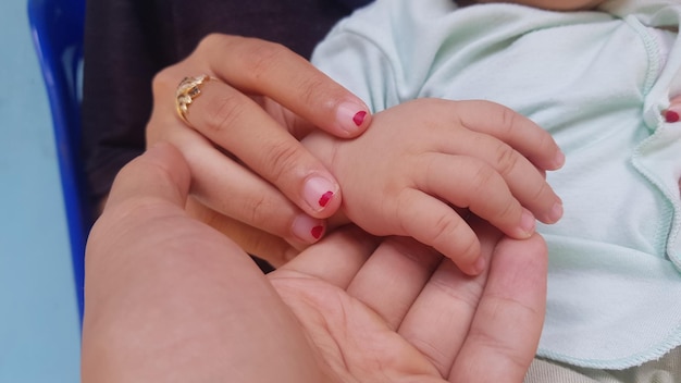 A baby's hand is held by a woman.