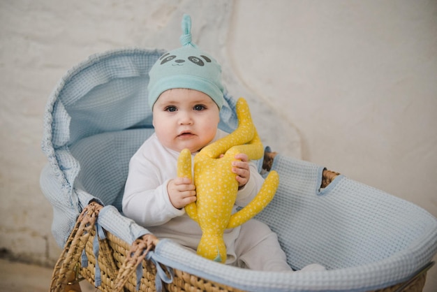 The baby sits in a wicker cradle. Little cute boy in a cradle.