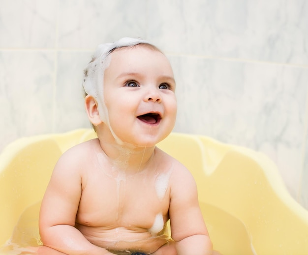 Baby sitting in bathtub with soapy hair