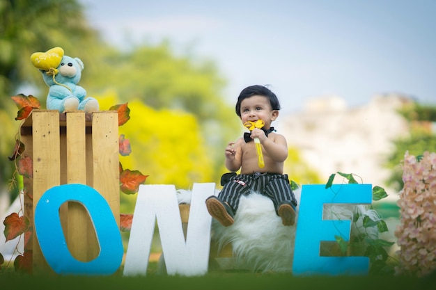 Baby sitting on box and letters around playing with spinner in hand in black pant