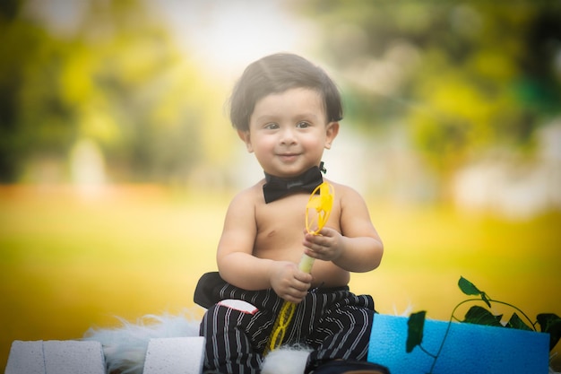 Baby sitting playing with spinner in hand in black pant with blurred background