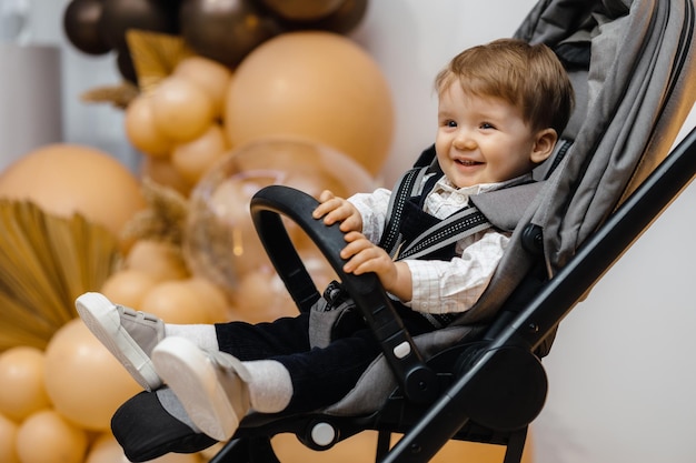 A baby in a stroller with balloons in the background