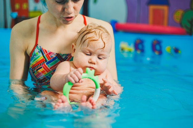 Baby swimming in the pool Teaching a newborn boy to swim in a pool with a coach