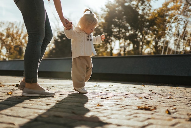 Photo baby takes her first steps in the park holding mom39s hand