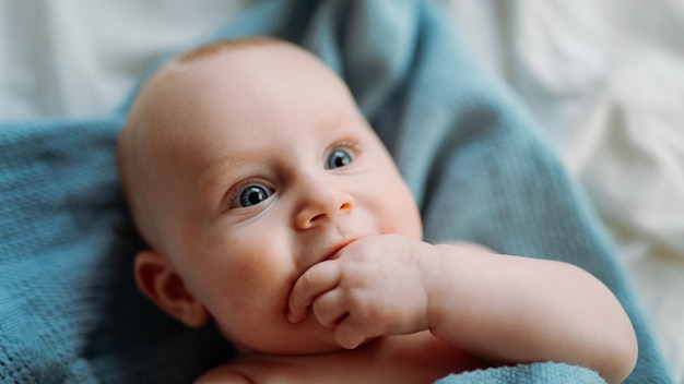 Baby toddler laying on the blue blanket smiling and looking away cover photo