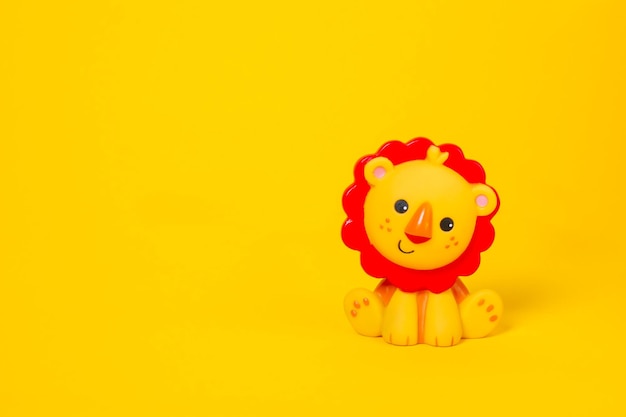 Baby toy lion made of plastic on a yellow background with copy space Cute children toy orange lion