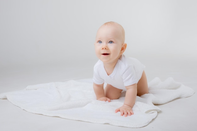 A baby in a white bodysuit crawls on a white background