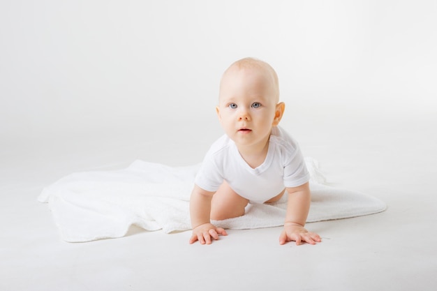 A baby in a white bodysuit crawls on a white background