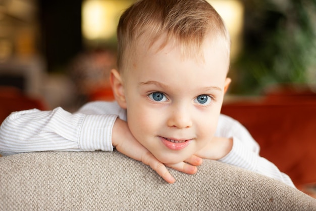 a baby with blue eyes is sitting on a couch