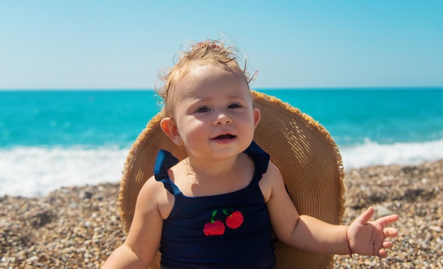 Baby with a hat on the beach. Selective focus.