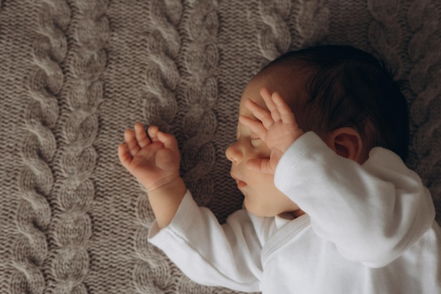 a baby with his eyes closed and the word baby is sleeping on the carpet