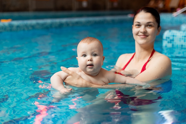 Baby with mom learns to swim in the pool