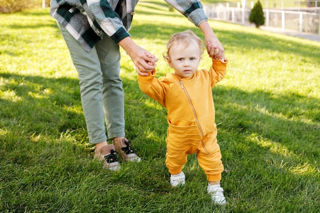 Baby with mom makes first steps in the park