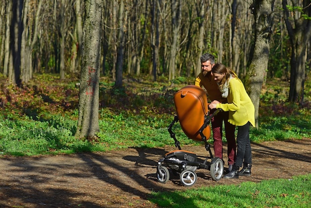 Babysitters walk with baby pram in park Woman and man babysitters take care of little child Responsibility and reliability Reliable care for precious little ones