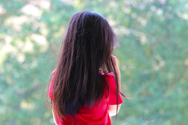 Back of Asian girl loneliness and crying waiting someone near the window unhappy at the school