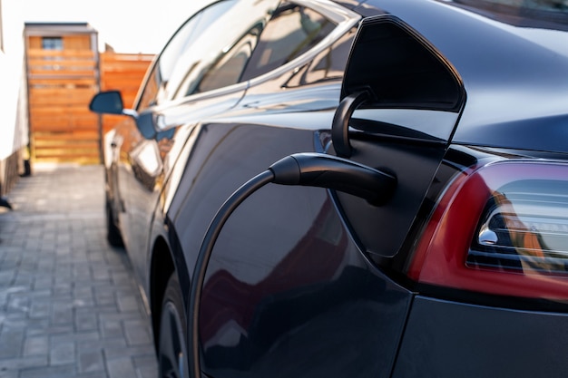 Back of black car with plugged charger during fueling process