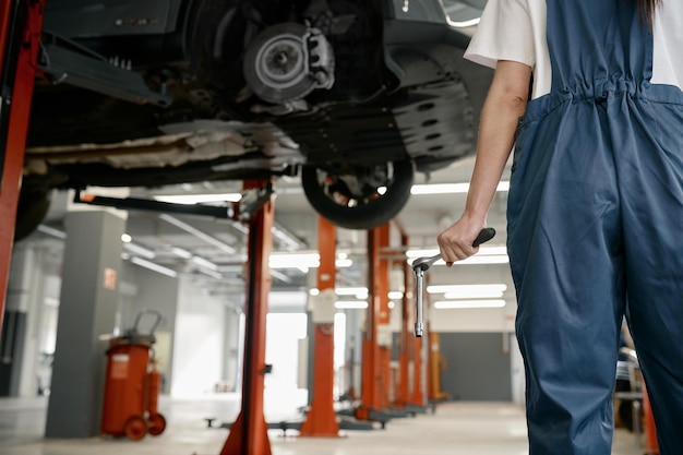 Back cropped view on female mechanic hand holding spanner wrench tool