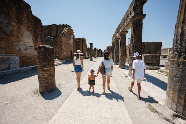 Back of family tourist walking at Pompeii ancient city Italy