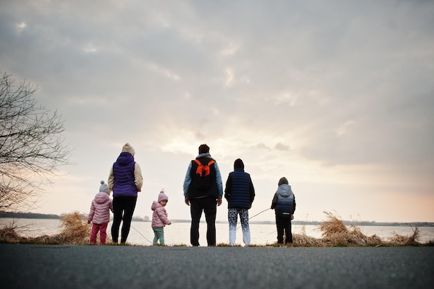 Back of family with four kids on the shore of the lake