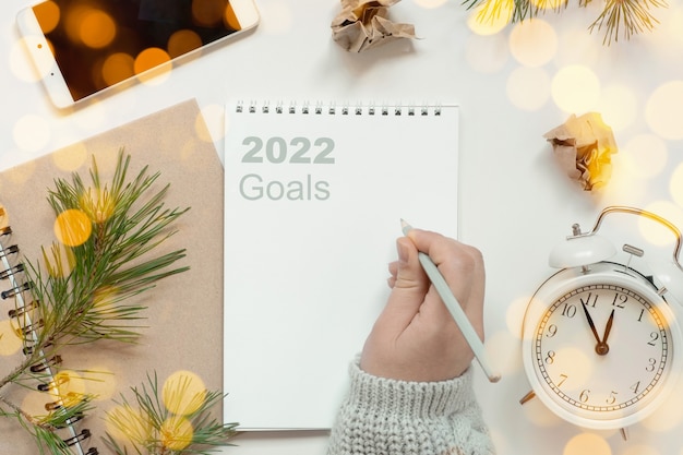 Photo back to life, goal list concept. woman's hand writing in empty notebook. resolutions, plan, goals, checklist, idea concept. top view, flat lay, copy space. 2022. christmas, new year