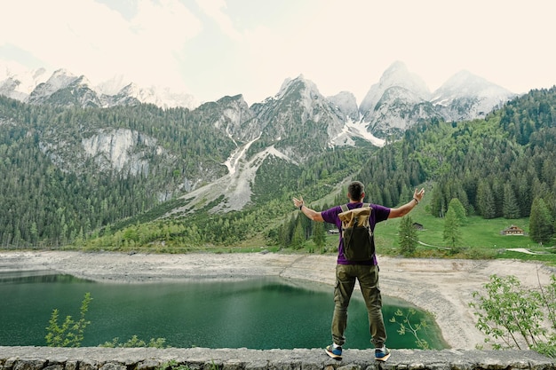 Back of man with backpack against lake and mountains at Vorderer Gosausee Gosau Upper Austria