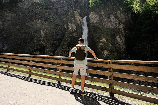 Back of man with backpack against waterfall in Liechtensteinklamm or Liechtenstein Gorge Austria