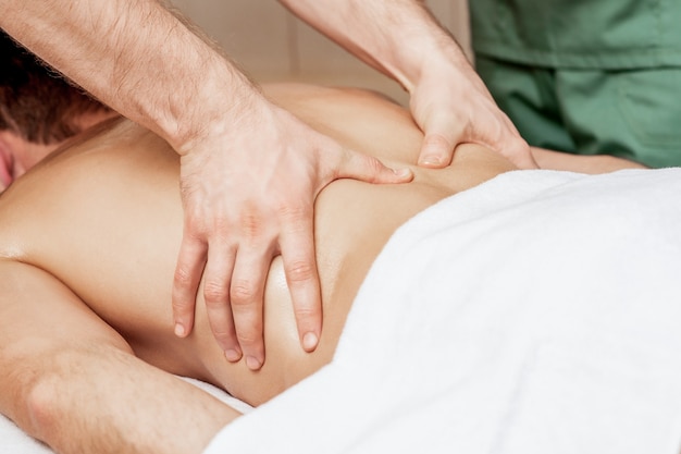 Back massage on back of man in spa salon.