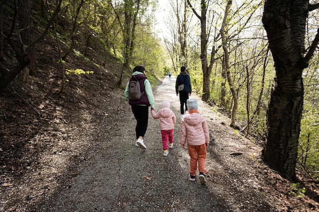 Back of mother with small children hiking outdoors in spring nature