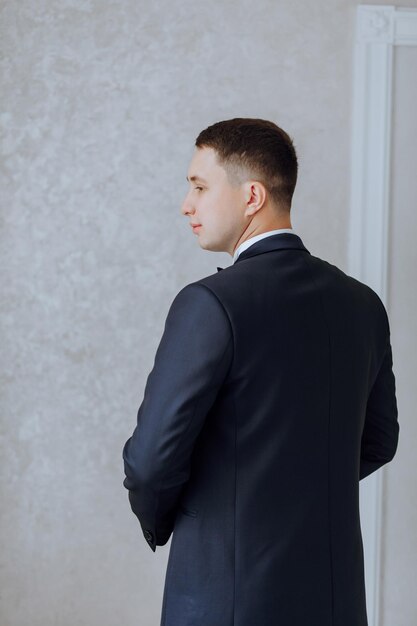 Back portrait of successful Caucasian man in formal suit posing in room happy young male boss or CEO showing confidence and strength leadership concept