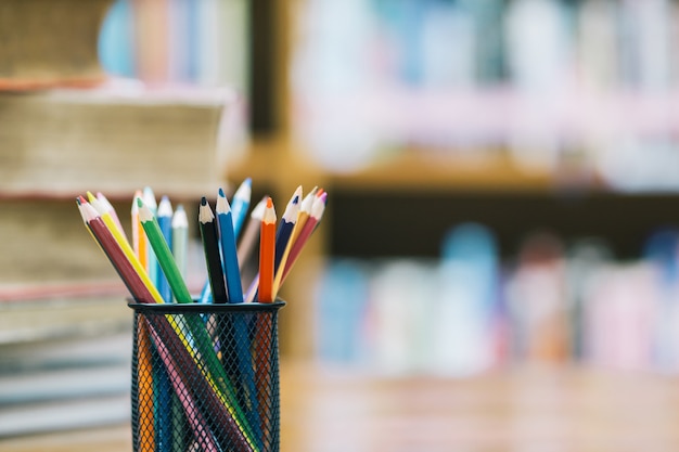 Back to school background with book and wooden color pencils in the basket