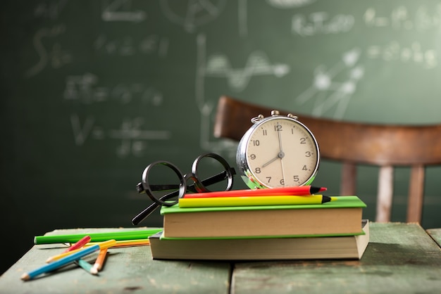 Back to school background with books and alarm clock over chalkboard. Back to school concept