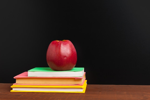 Back to school concept. Blackboard with books and apple on wooden desk