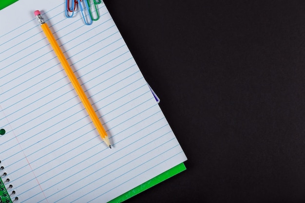 Back to school concept blank notebook pencil pen ruler and scissors notebook and pencil on a black b