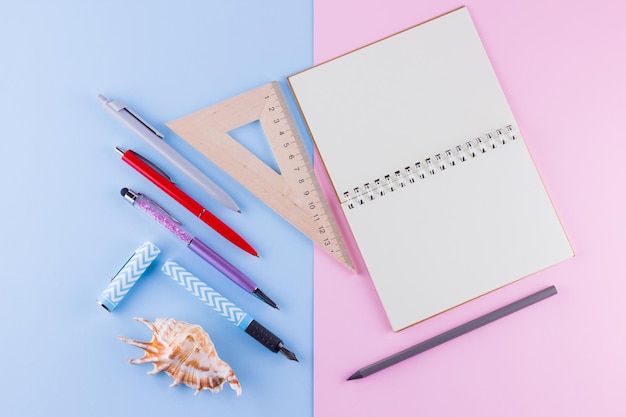 Back to school concept School stationery and seashell on pink blue background Pens pencil and gon