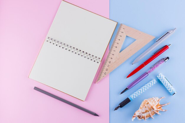 Back to school concept School stationery and seashell on pink blue background Pens pencil and gon