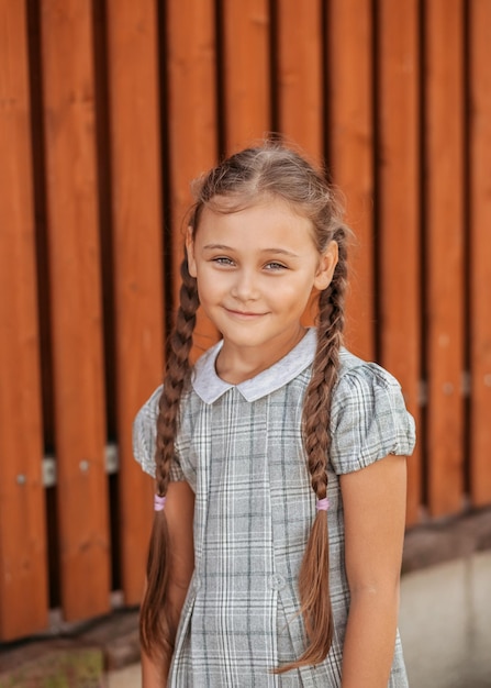 Back to school A cute little schoolgirl in a dress with pigtails walks in the school yard A little girl is going to the first grade