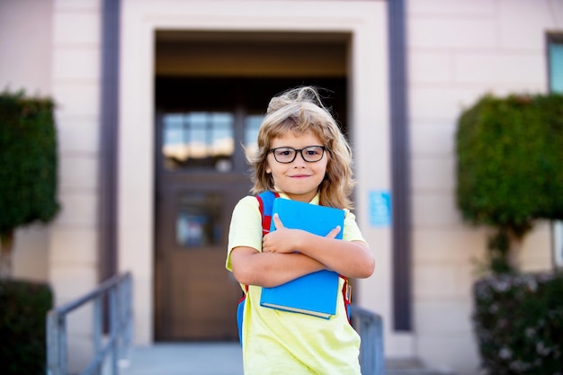 Back to school Funny little boy in glasses at school Child from elementary school with book and bag Education child