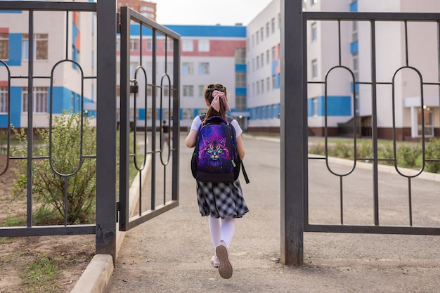 Back to school Girl in school uniform go to school with backpack behind their backs Beginning of lessons First day of autumn Elementary school student