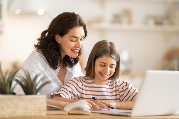 Back to school. Happy child and adult are sitting at desk. Girl doing homework or online education.