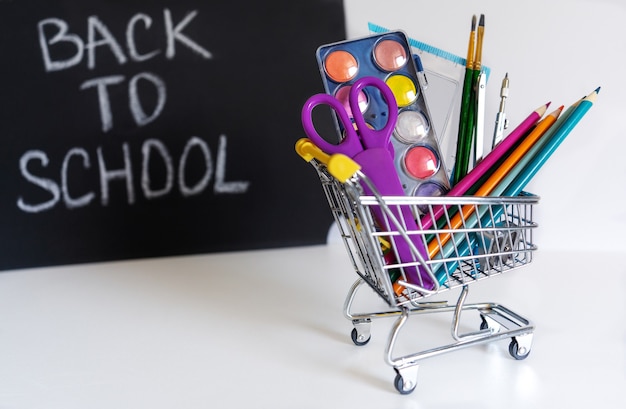 Back to school. Mini shopping cart with pencils and school supplies on a white background. School banner