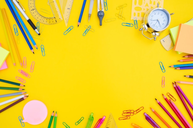 Back to school or office styed scene with multicolored school supplies on yellow background