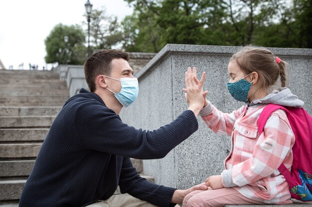 Back to school, pandemic. Young father and little daughter in a mask.