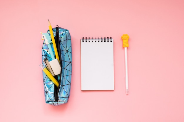 Back to school. Pencil case with school supplies on pink table