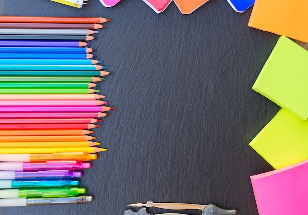 Back to school pencils and notes raibow, copy space on black board, top view, hero header