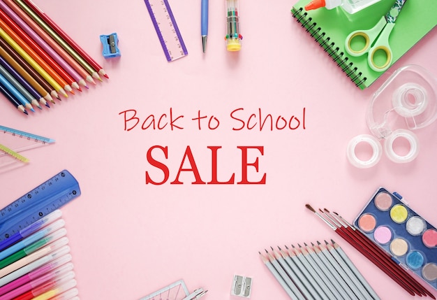 Back to school Sale text and colored pencils, notebooks, a ruler, felt-tip pens, on a pink background. Banner