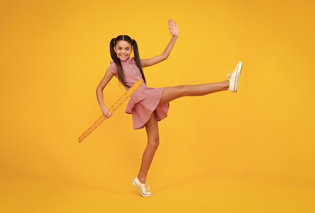 Back to school School girl hold ruler measuring isolated on yellow background Crazy jump jumping kids Happy teenager positive and smiling emotions of teen schoolgirl