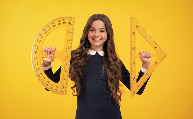 Back to school School girl hold ruler measuring isolated on yellow background